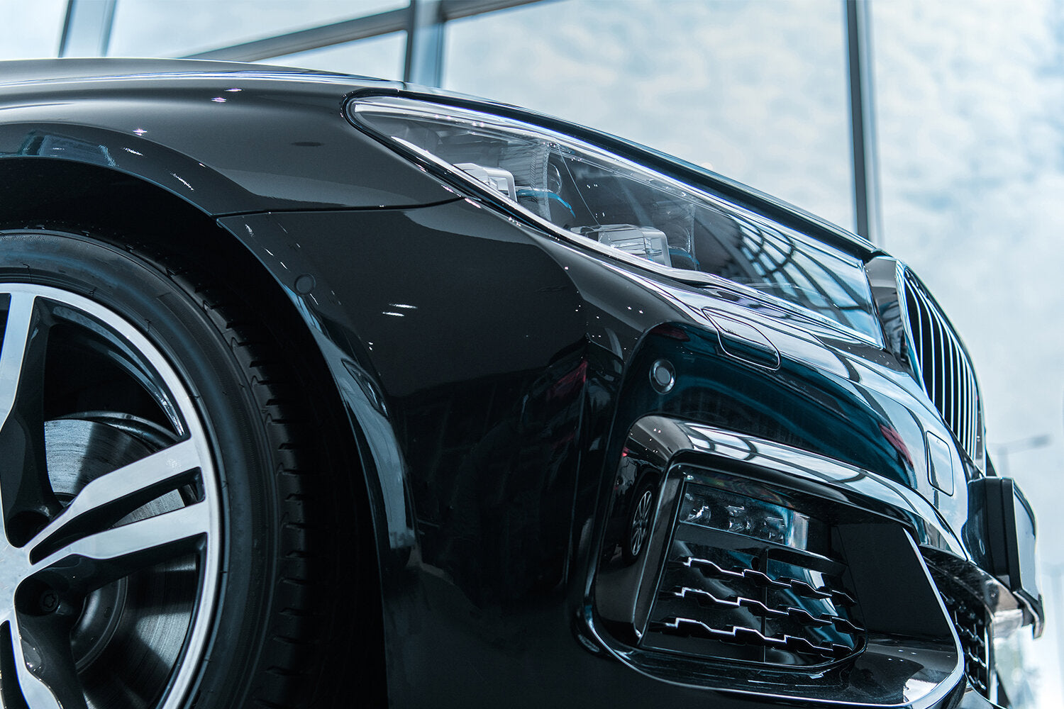 Closeup of black vehicle headlight and front tire