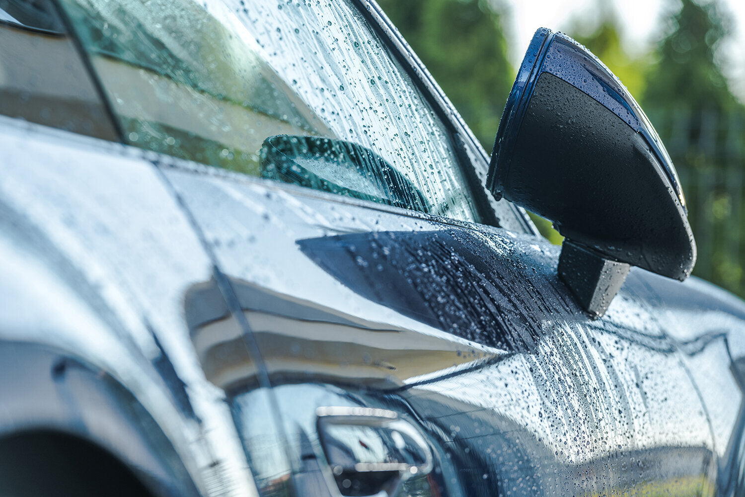 Closeup of car side mirror and door in rain