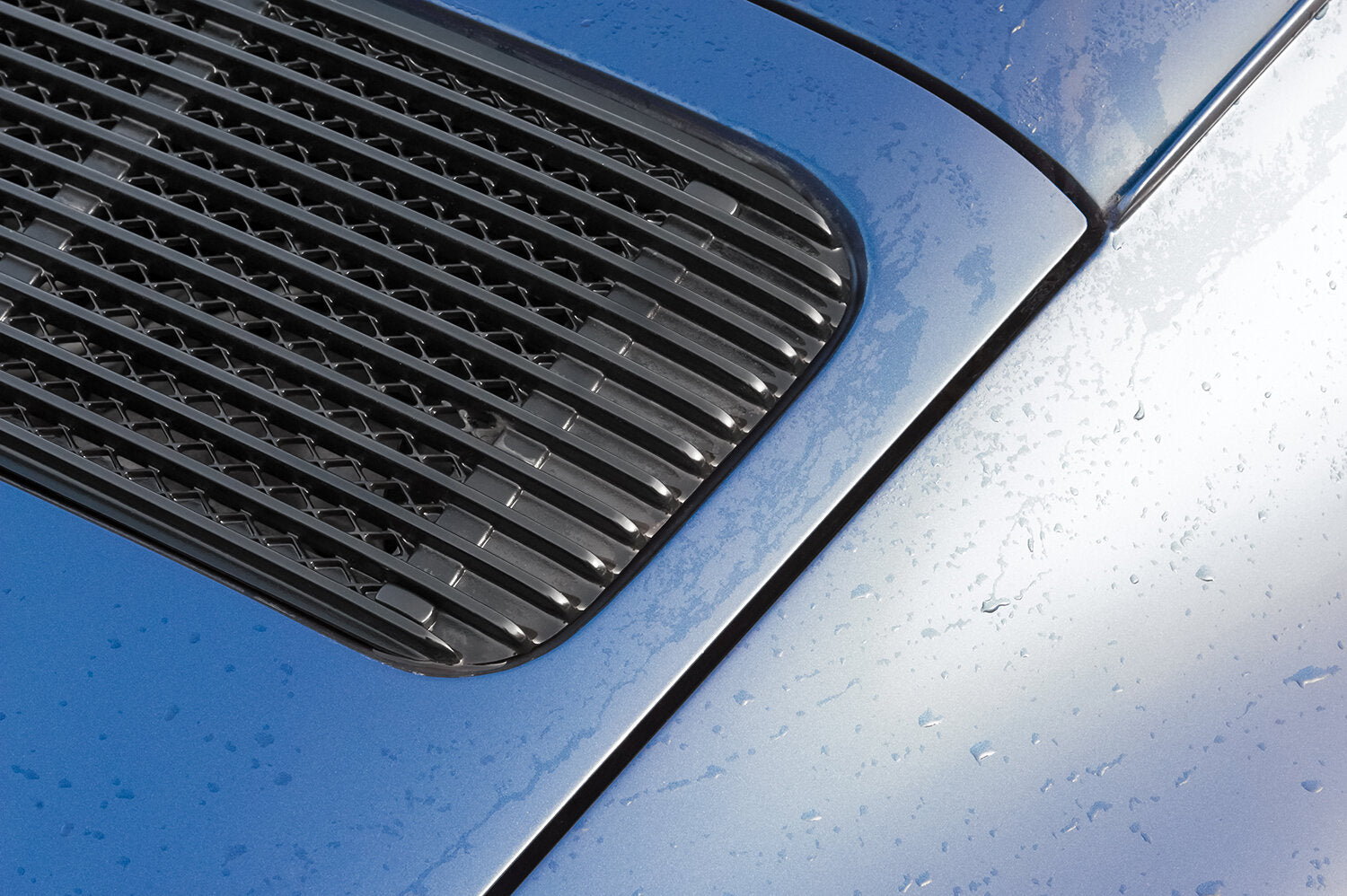 Closeup of blue vehicle with raindrops on exterior