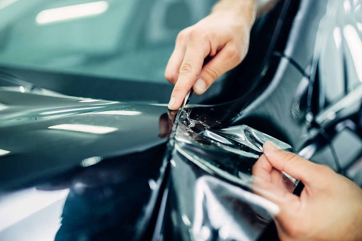 Worker installing paint protection on vehicle