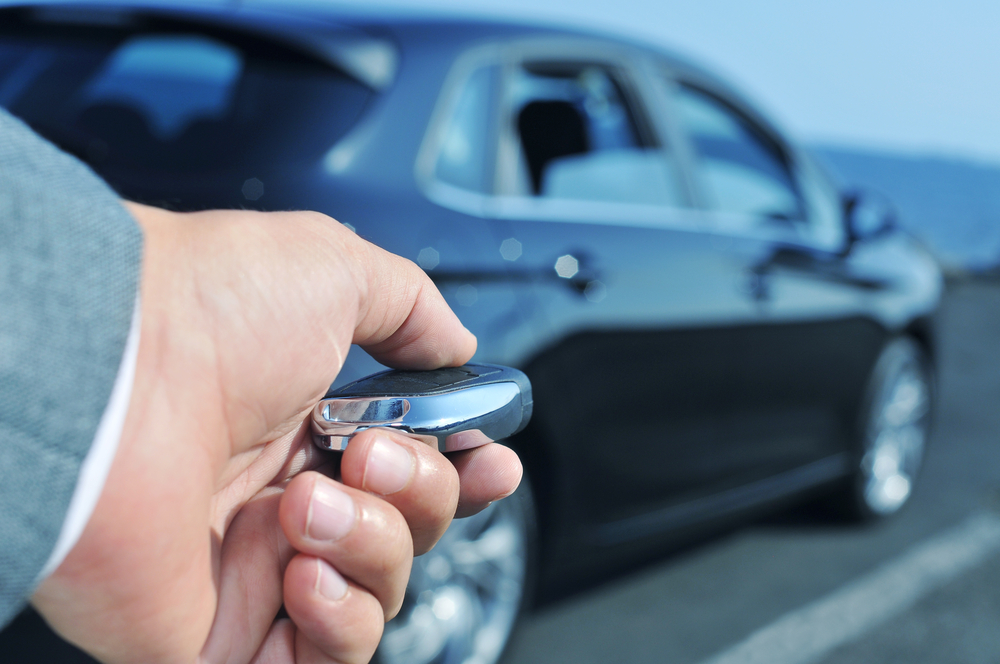 A hand is pressing the car remote control