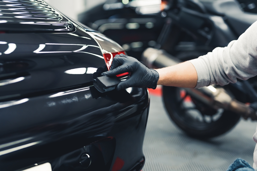 Hands with black gloves is applying a ceramic coating