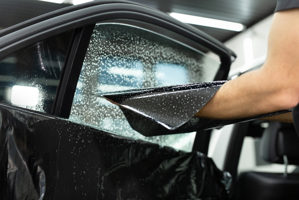 Visible hand of a car styler is holding a wet window film tint